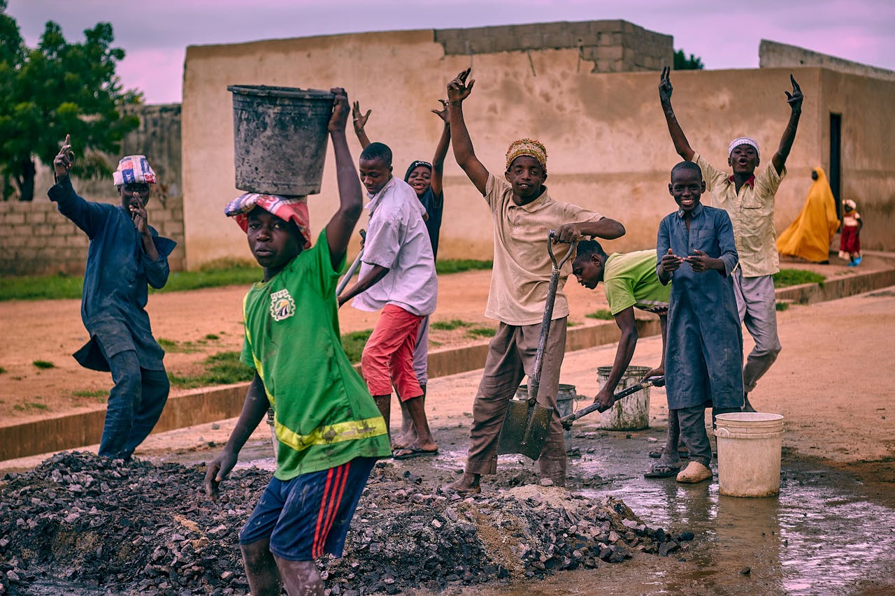 A group of young workers smiling and posing at a construction site in an urban setting.
