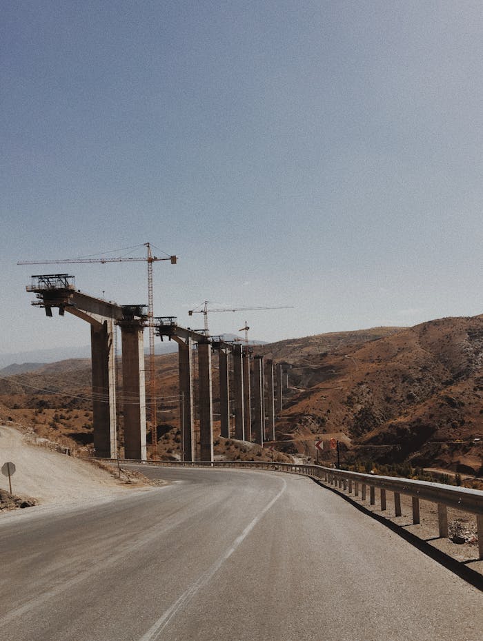 View of cranes constructing a bridge in Hadim, Turkey over a rural road.